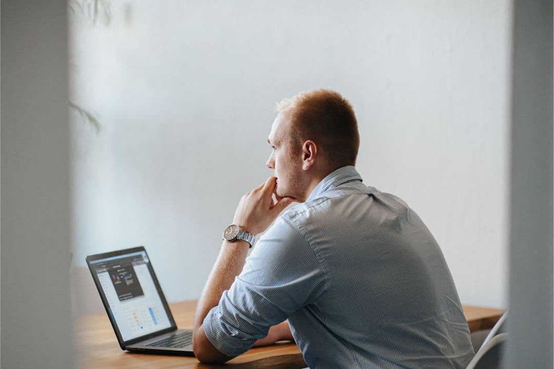 Foto von Simon Reinkober vor einem Laptop an einem Schreibtisch