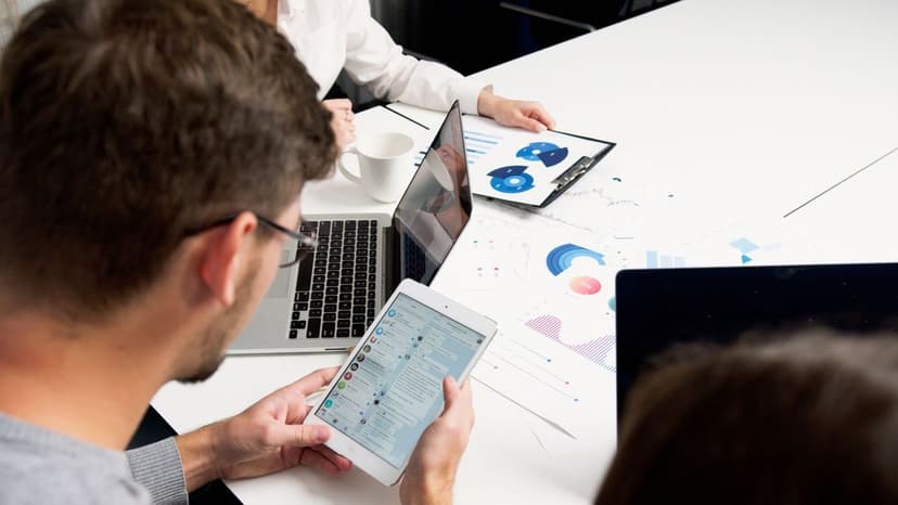 Mehrere Personen analysieren Social-Media-Daten und Chatverläufe an Laptops und Tablets